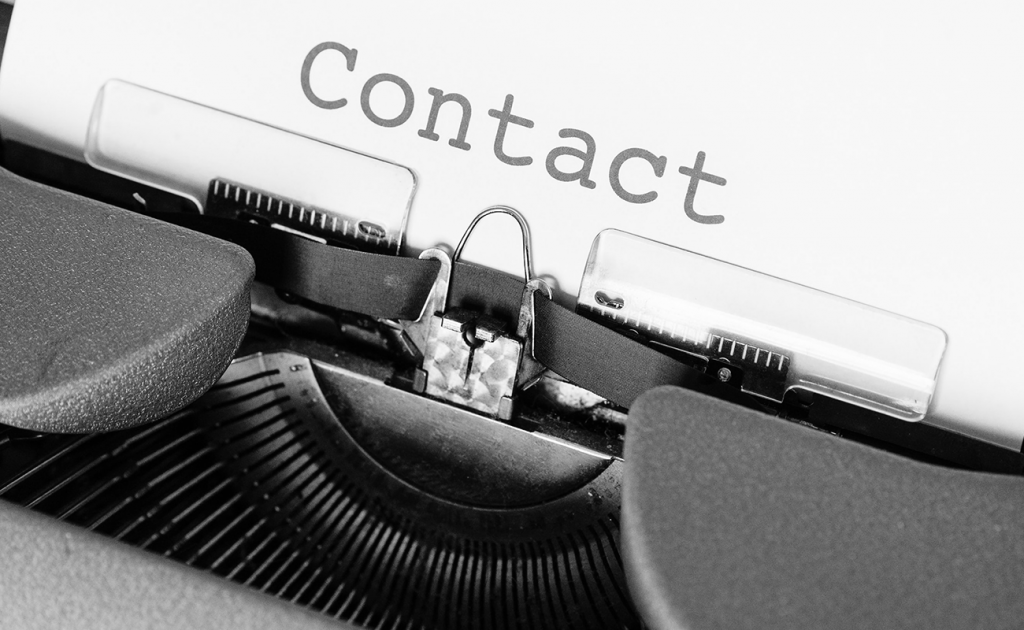 Close up view of a typewriter ribbon section with the word 'Contact' typed on the paper.