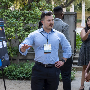 Photograph of Nick Geiser presenting a poster at an outdoor poster session.